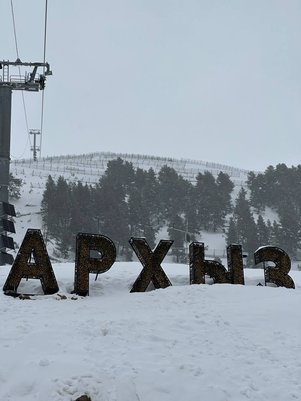 Табличка «Архыз» на фоне заснеженных склонов